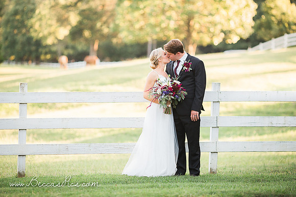 Wedding couple at dewberry farm in kernersville nc with fence and horses behind in field